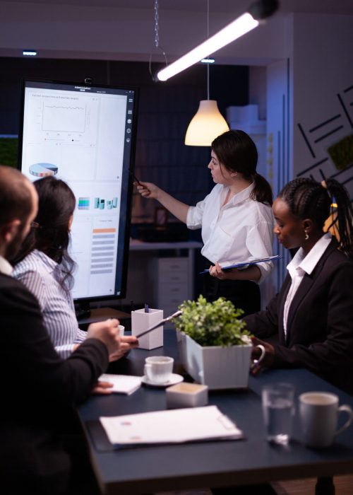 Executive manager woman explaining management statistics working at company strategy Executive manager woman explaining management statistics working at company strategy overtime in office meeting room. Diverse multi-ethnic businesspeople teamwork brainstorming ideas in evening.