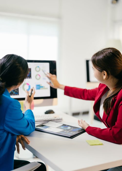 Two businesswomen discussing financial data on a computer, strategizing for the future with teamwork and collaboration Two businesswomen discussing financial data on a computer, strategizing for the future with teamwork and collaboration